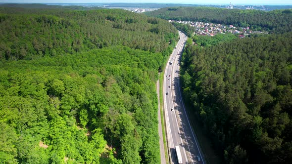 Traveling On The European Route Through Dense Green Forest In Gdynia, Poland. aerial tilt down alt