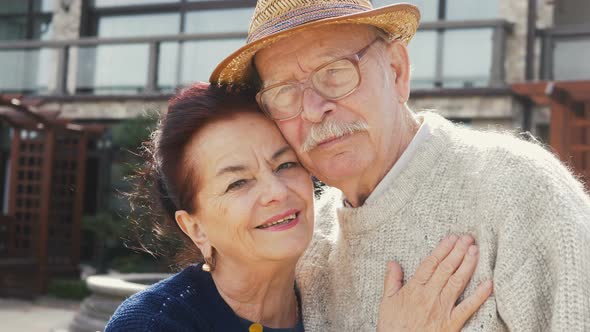 Elderly married couple smiling embracing. Happy old husband hugging his beautiful wife. Long term te