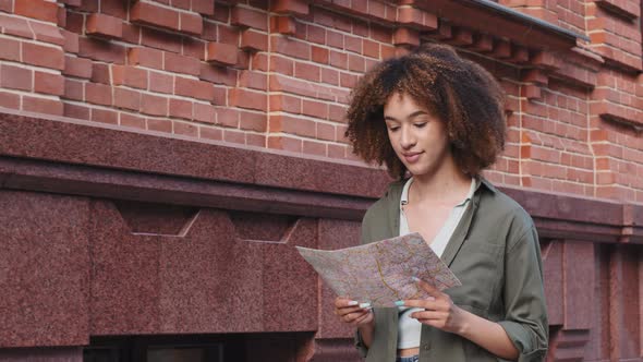AfroAmerican Girl Looks Around Lost with Paper Map in Downtown alt