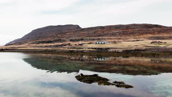 Remote Building And Mountain Landscape Reflected In Fjord alt