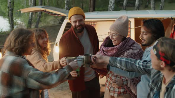 Friends Toasting and Drinking from Cups at Campsite alt