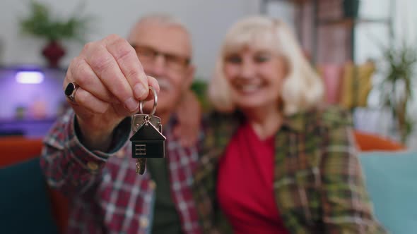 Happy Senior Family Couple Grandparents Man Woman Looking at Camera Demonstrating Keys From New Flat alt