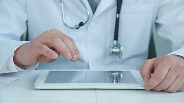 Man Doctor Sitting In Hospital Office And Using Digital Tablet alt