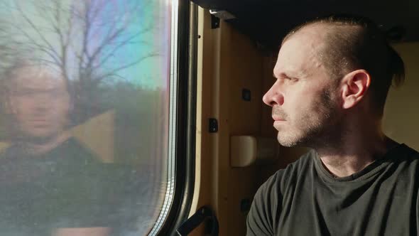 Portrait of a Man Sitting in a Train Car and Looking Out the Window