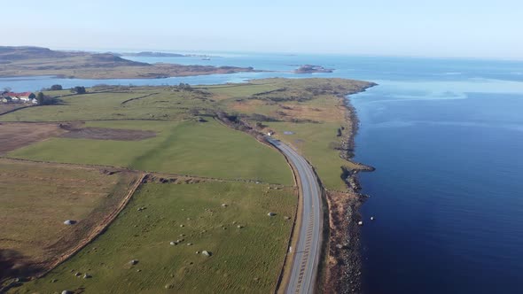Road E39 along Norway coast is surrounded by green grasslands and going down into subsea tunnel Byfj alt