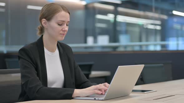 Businesswoman Showing Thumbs Down While Using Laptop alt