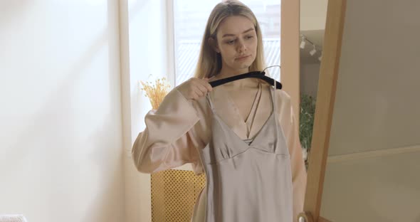 Woman Shopping For Clothes Looking In Mirror In Clothing Store alt