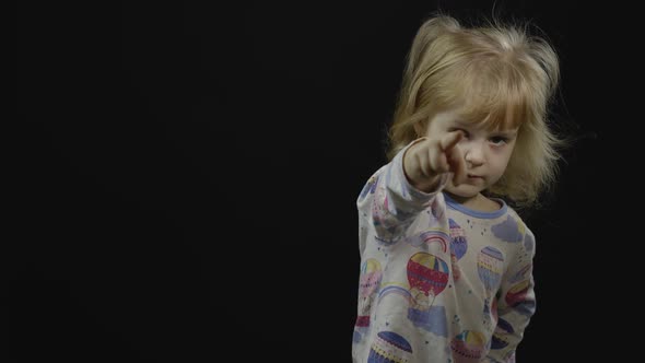 Little Baby Girl in Pajama Is Fooling Around and Make Faces. Black Background alt