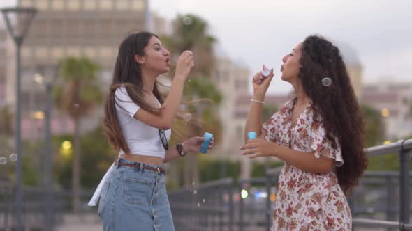 Happy Teenage Girls Blowing Soap Bubbles on Pier Slow Motion
