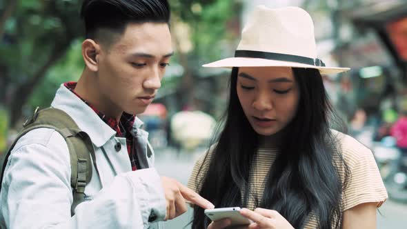 Handheld view of Vietnamese couple of tourists choosing the best path for travel  alt