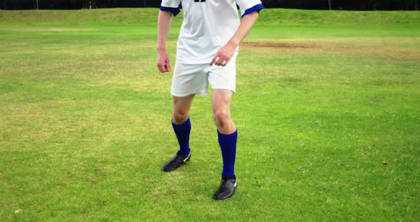 Football player striking a ball in the field alt