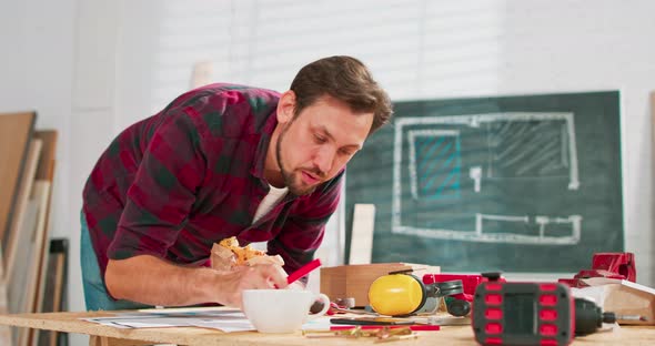 A Carpenter Uses a Smartphone During a Break at Work A Handsome Carpenter in a Flannel Shirt Counts alt