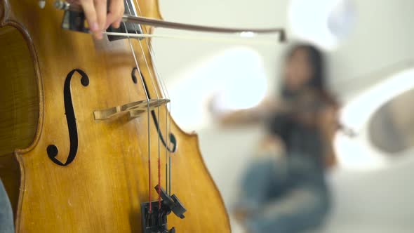 Closeup of a Playing the Cello in the Background Playing the Violin alt