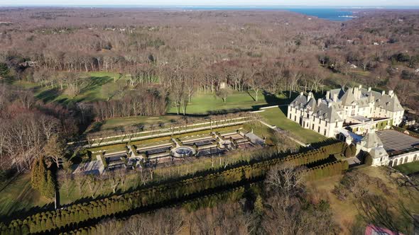 An aerial view over a large, upscale, luxury mansion with an eight reflection pool fountain, on Long alt