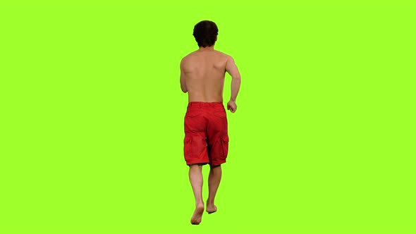 Back View of a Shirtless Man Jogging in Red Shorts 