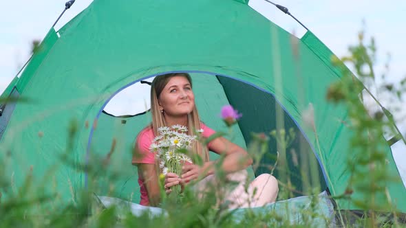 The Girl is Resting in a Tent in the Mountains She is Holding Chamomile Flowers in Her Hands alt