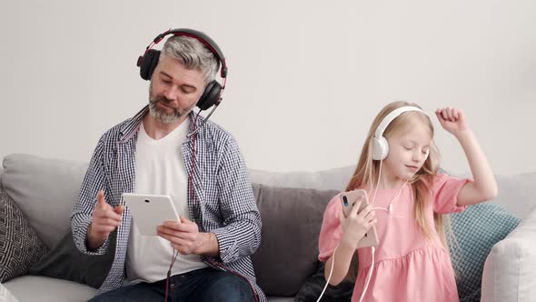 Little Girl Listening Music in Headphones with Grandfather alt