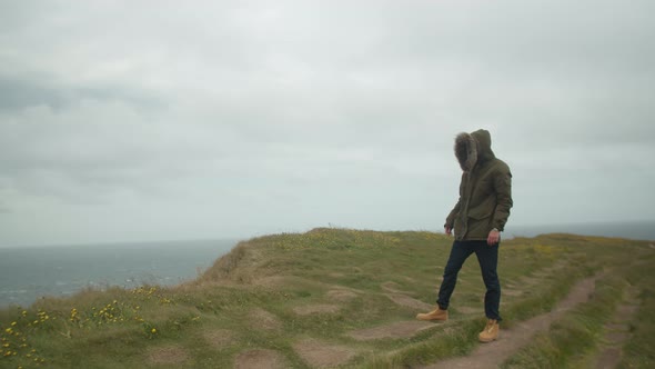 Caucasian Man Standing Near The Edge Of A Cliff In Iceland Coast During Windy Stormy Day alt