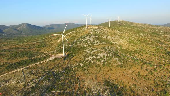 Flying above elegant ecological wind turbines on green hills alt