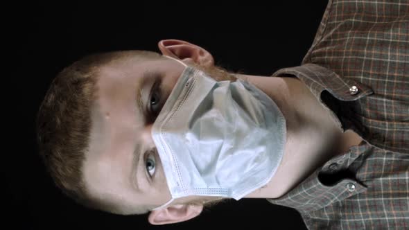 Vertical Shot Young Man on Black Background in Medical Mask Against Covid19 Put on Glasses