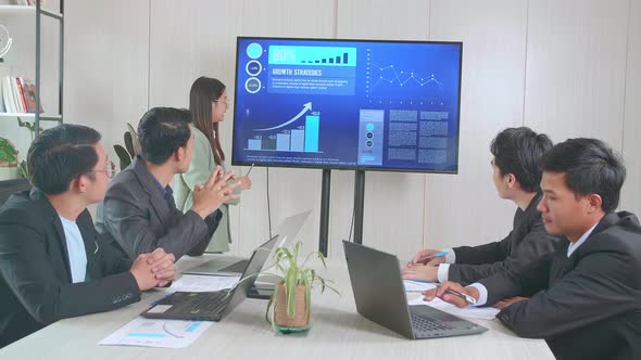 Asian Businesswoman Presentation To Her Business Colleagues, Pointing At Charts On Tv Screen alt