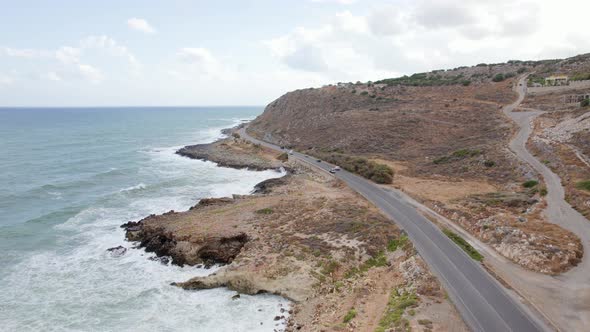 Traffic along cinematic winding mountain road. Epic aerial drone shot of cars