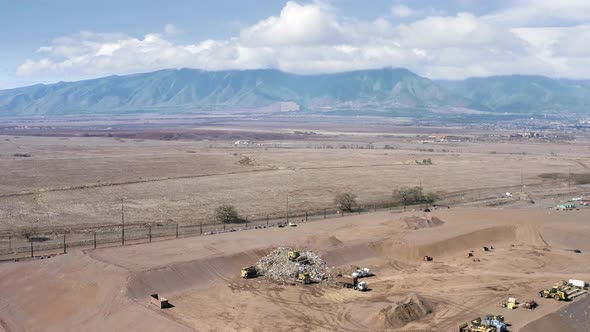Workers at Landfill with Hawaiian Mountains on Background Blue Sky and Clouds alt