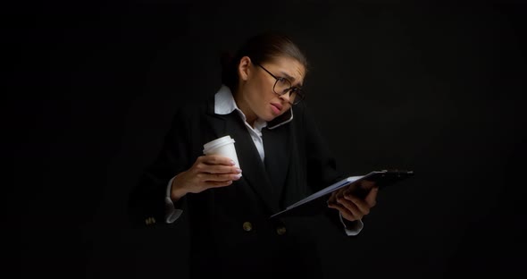 Busy Woman Holds Coffee and Documents in Her Hands Talking on Phone