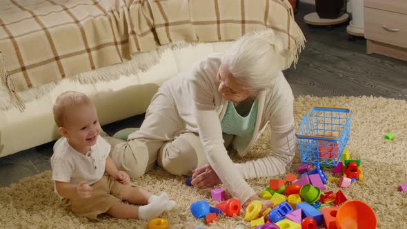 Cute Baby Boy Sitting on Floor with Grandmother and Playing