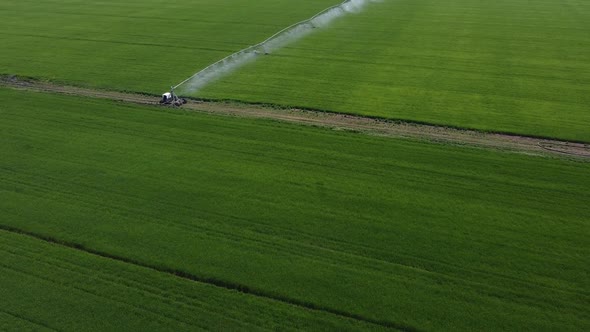 Aerial view of circular irrigation watering agricultural equipment on a young green field of wheat