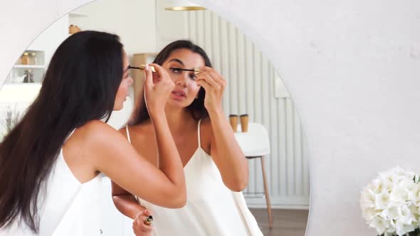 Brunette Woman with Long Straight Dark Hair and Clean Skin Doing Make Up Routine alt