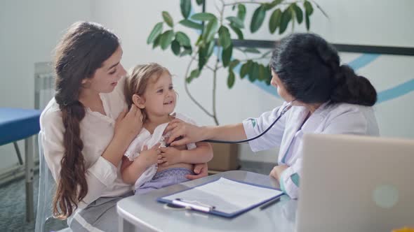Female Doctor Pediatrician Using Stethoscope Listen To the Heart of Happy Healthy Cute Kid Girl