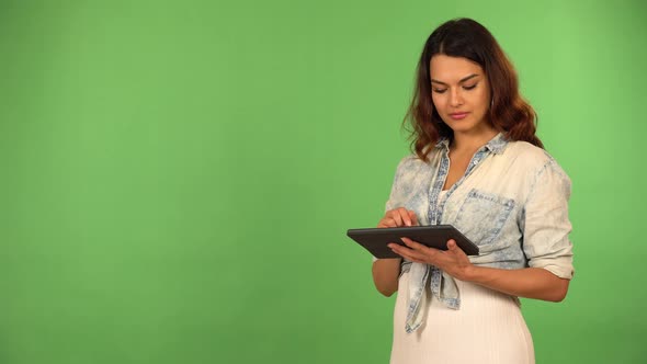 A Young Beautiful Caucasian Woman Works on a Tablet Then Smiles at the Camera  Green Screen