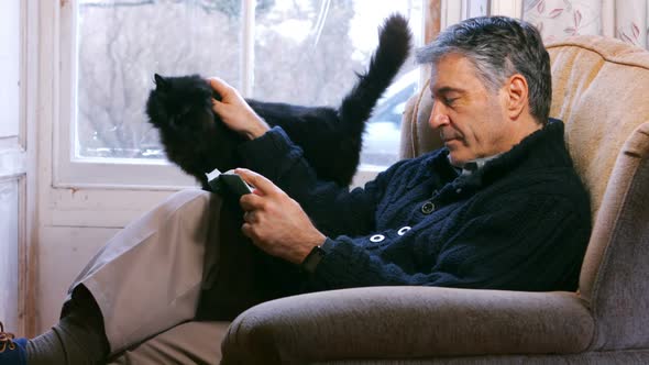 Man reading book in living room at home alt