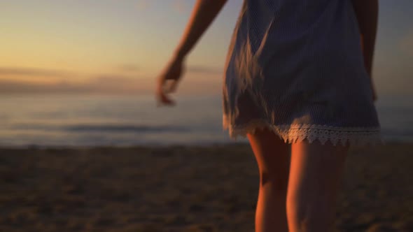 Close Backside View of Young Woman Running at Sea on the Beach Wearing Blue Summer Dress During alt