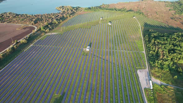 Aerial View Solar Power Station on Green Field at Sunset Solar Panels in Row alt
