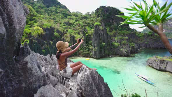 Woman Sitting On Limestone Rocks Taking Photo With Smartphone alt
