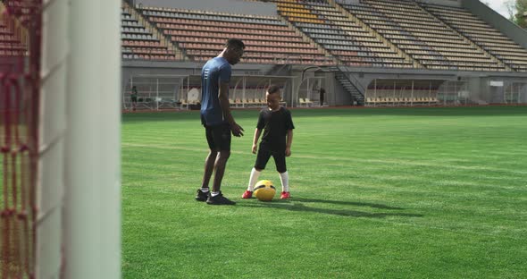 Black Coach Talking with Kid About Football on Stadium alt
