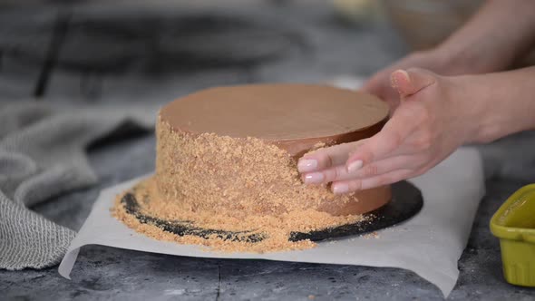 Female Hands Use the Crumbs to Decorate the Sides of the Cake