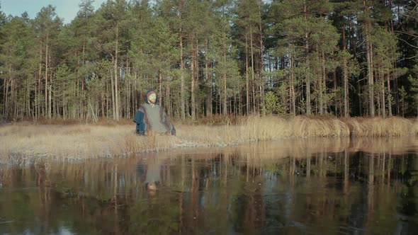 TRACKING REVERSE shot of an ice bather doing conscious breathing by a frozen lake alt