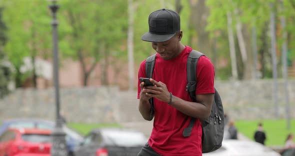 African American Man in Red T-shirt Laugh Using App on Smart Phone alt