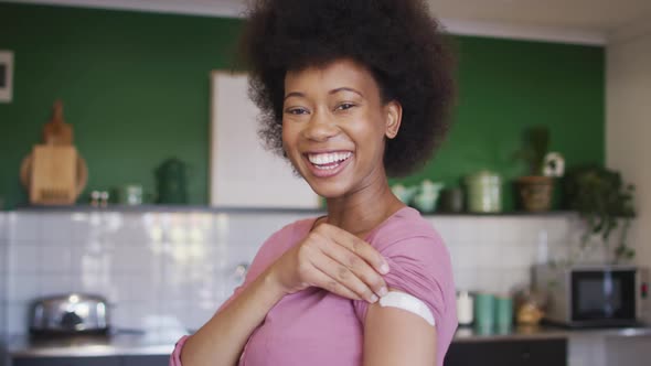 Happy african american senior woman showing plaster on arm after covid vaccination alt