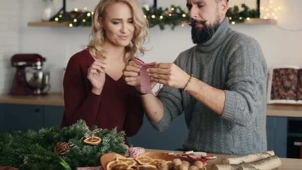 Blonde woman teaching men how to make Christmas bow. Shot with RED helium camera in 8K alt
