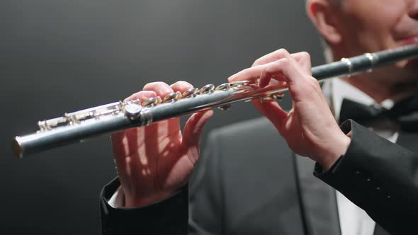 Musician is Playing Flute in Opera House or Modern Music Hall Closeup of Male Hands with Flute alt