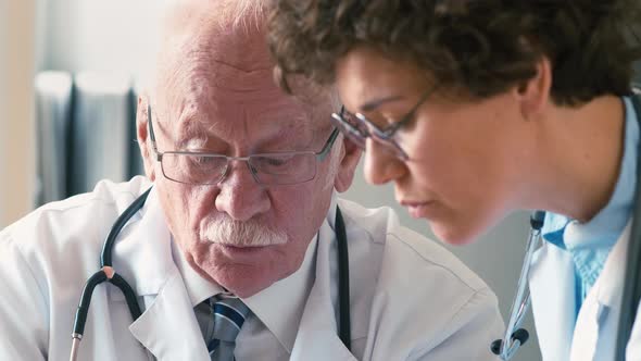 Old and young doctors discussing medical history sheet