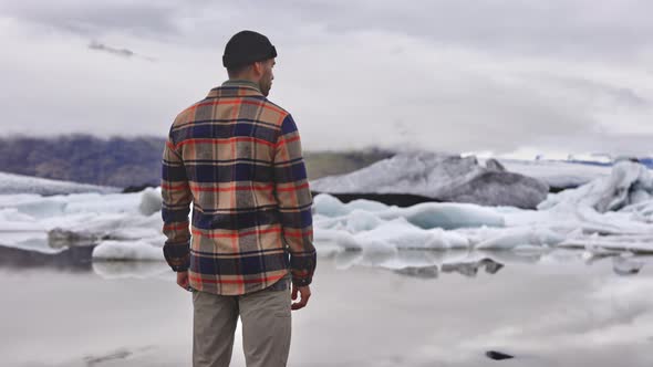 Man in Plead Shirt Admiring Beautiful Glaciers Melting By the Lake in Iceland alt