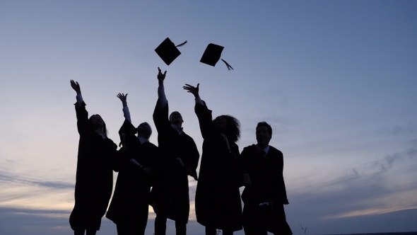 Silhouette of Graduating Students Throwing Caps In The Air. alt