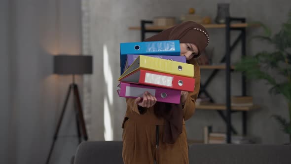 Portrait of Shocked Middle Eastern Young Woman Standing in Home Office with Document Folders Sighing alt