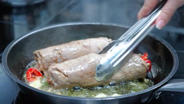 Chef is Cooking Two Meat Rolls in Oil on a Frying Pan Closeup in Slow Motion