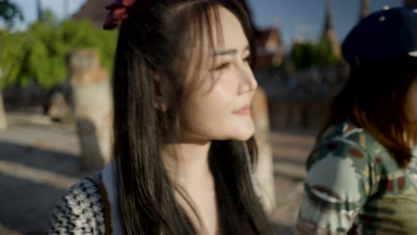 Asian Thai Girl Cover Face From Bright Sun with Hand While Walking Visiting Wat Yai Chai Mongkhon alt